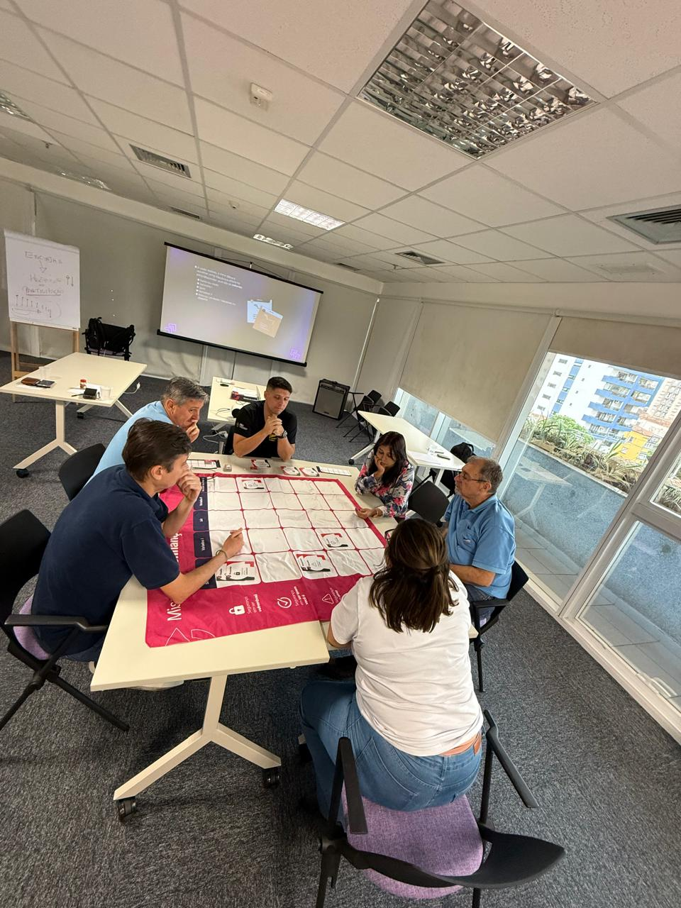 Participantes jogando Missão de Confiança em uma sala de treinamento da Rising