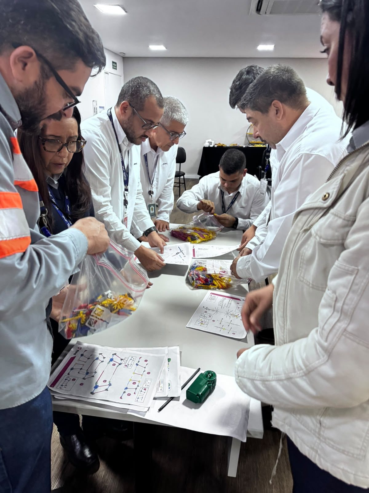 Equipe montando estruturas com peças e instruções durante dinâmica de treinamento corporativo da Rising