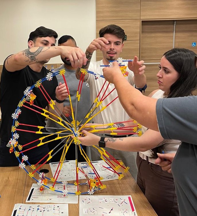 Equipe montando uma roda gigante com peças durante a dinâmica Looping, em treinamento corporativo da Rising